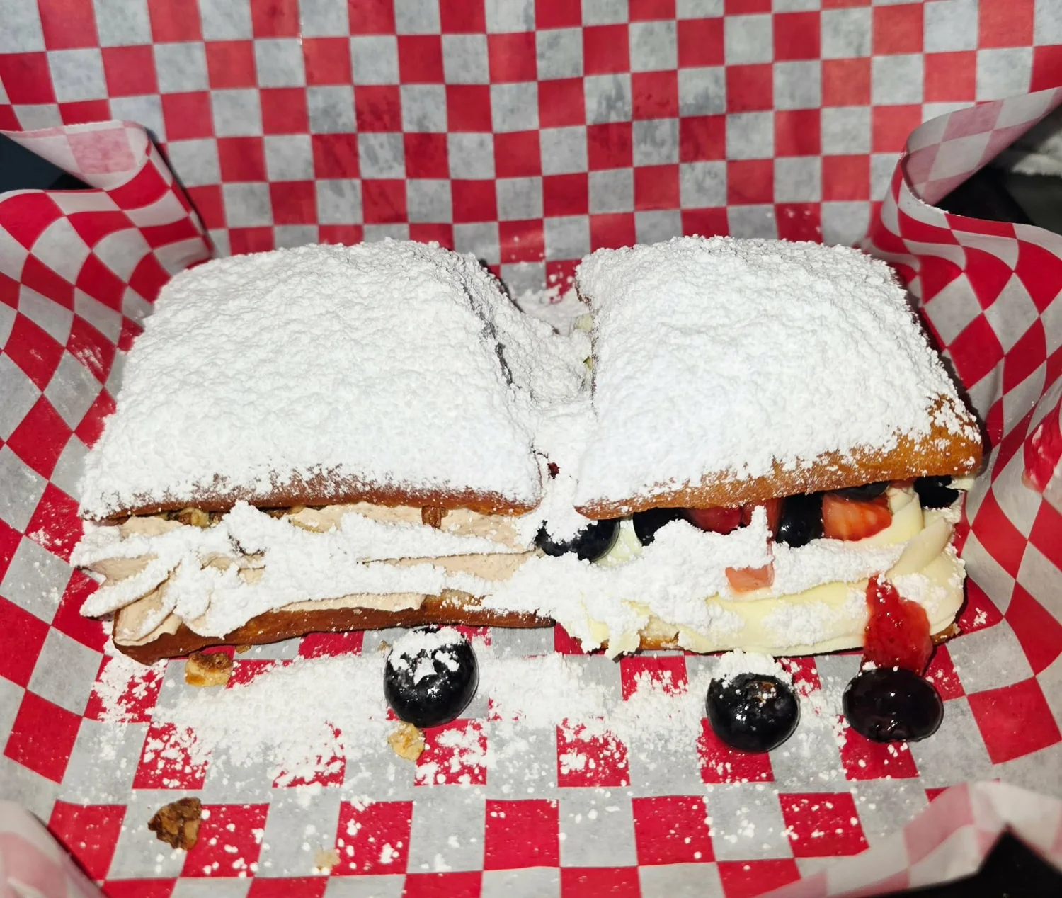 A box of dessert beignets filled with pecans and berry Chantilly cream.